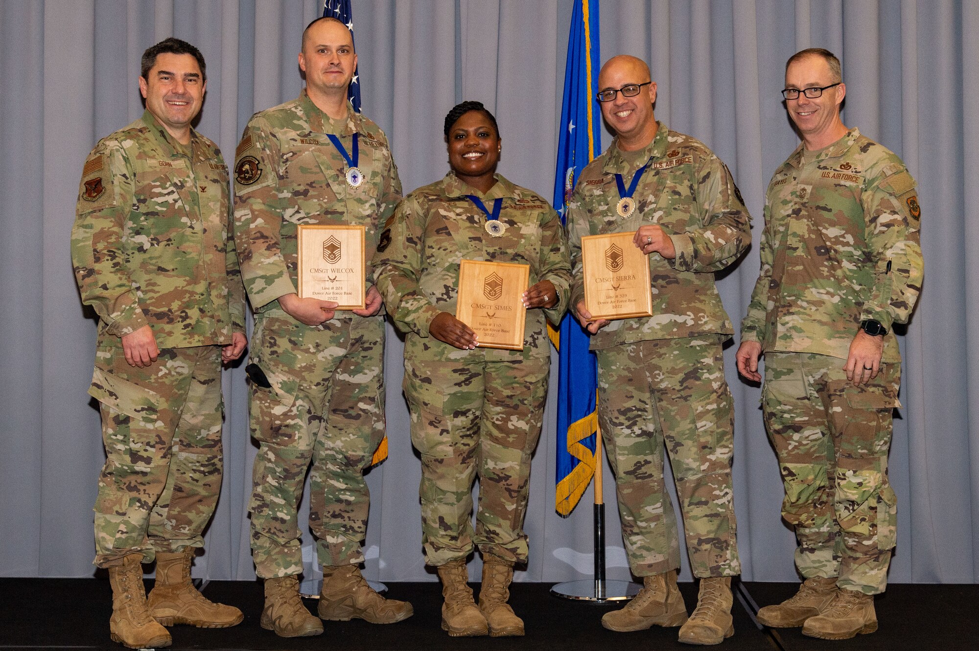 Col. Rusty Gohn, far left, 436th Airlift Wing vice commander, and Chief Master Sgt. Timothy Bayes, far right, 436th AW command chief, stand with Senior Master Sgts. Paul Wilcox, second from the left, 436th Security Forces Squadron operations superintendent; Shonta Simes, center, Air Force Mortuary Affairs Operations superintendent of operations support; and Michael Sierra, second from the right, 436th Logistics Readiness Squadron material management flight superintendent; for a photo during the chief master sergeant release party held at The Landings on Dover Air Force Base, Delaware, Dec. 8, 2022. The three are Dover AFB’s newest chief master sergeant-selects. (U.S. Air Force photo by Roland Balik)