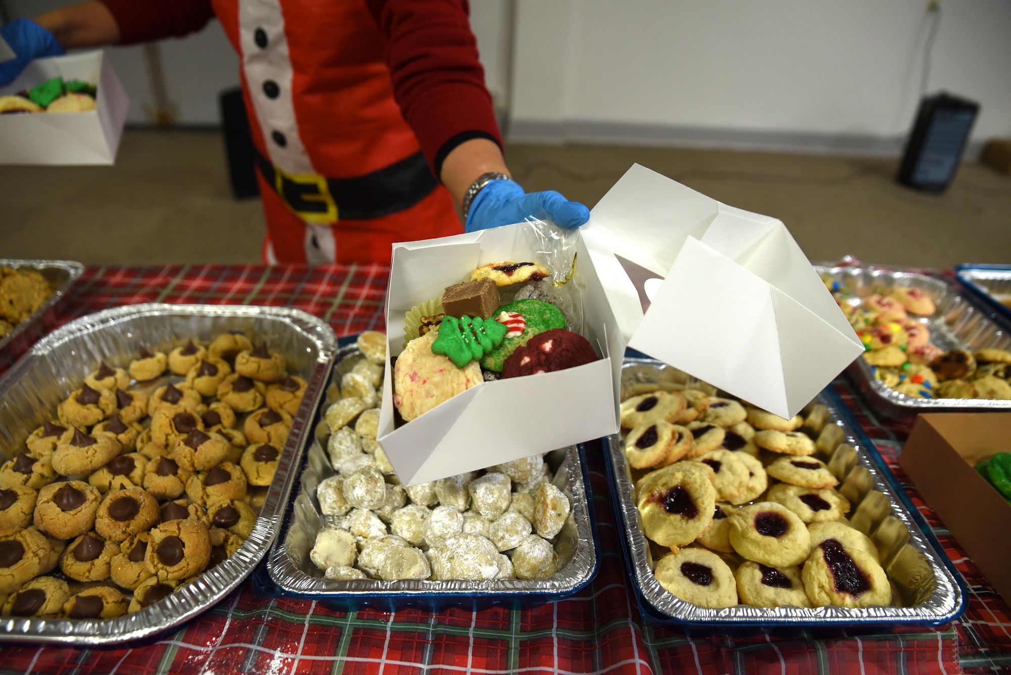 Team McChord volunteers organize cookies into a box during Operation Cookie Drop at Joint Base Lewis-McChord, Washington, Dec. 14, 2022. The goal of Operation Cookie Drop is to spread holiday cheer by giving single Airmen a dozen home-baked cookies provided by the McChord community. (U.S. Air Force photo by Airmen Kylee Tyus)