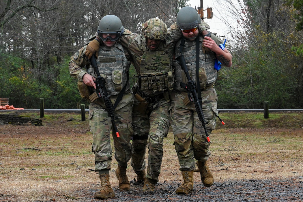 Two Airmen carry another Airman.