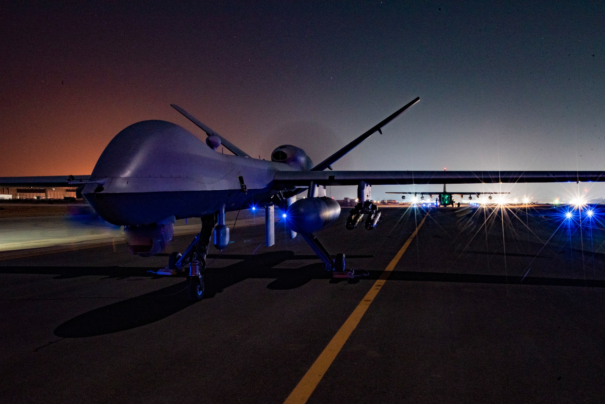 A 361st Expeditionary Attack Squadron MQ-9 Reaper and a 26th Expeditionary Rescue Squadron HC-130J Combat King II on a flight line at an undisclosed location, Southwest Asia, Dec. 10, 2022, as part of a Forward Arming and Refueling Point mission.  (U.S. Air Force photo by: Tech. Sgt. Jim Bentley)
