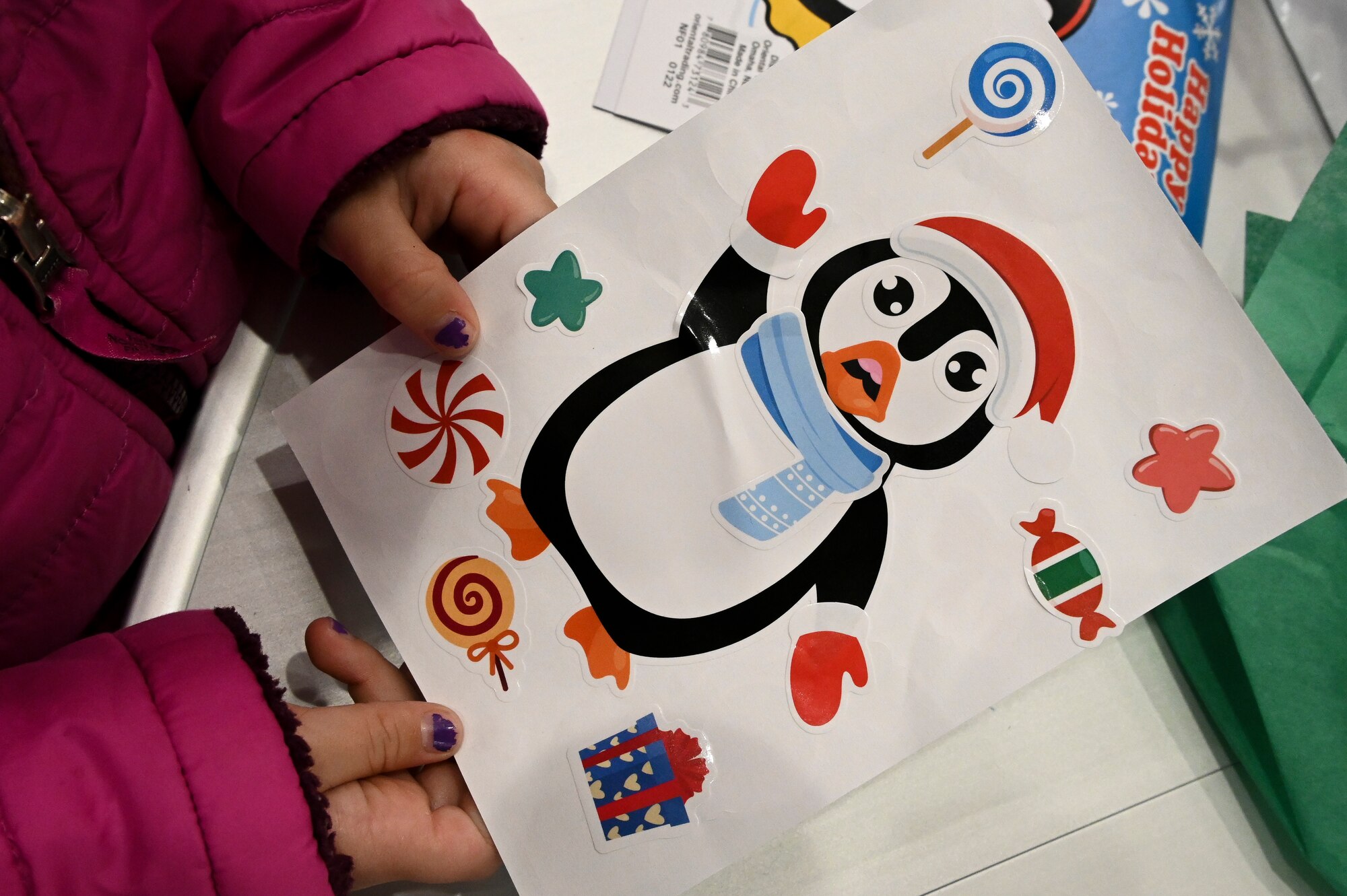 Child holds picture of penguin winter art.