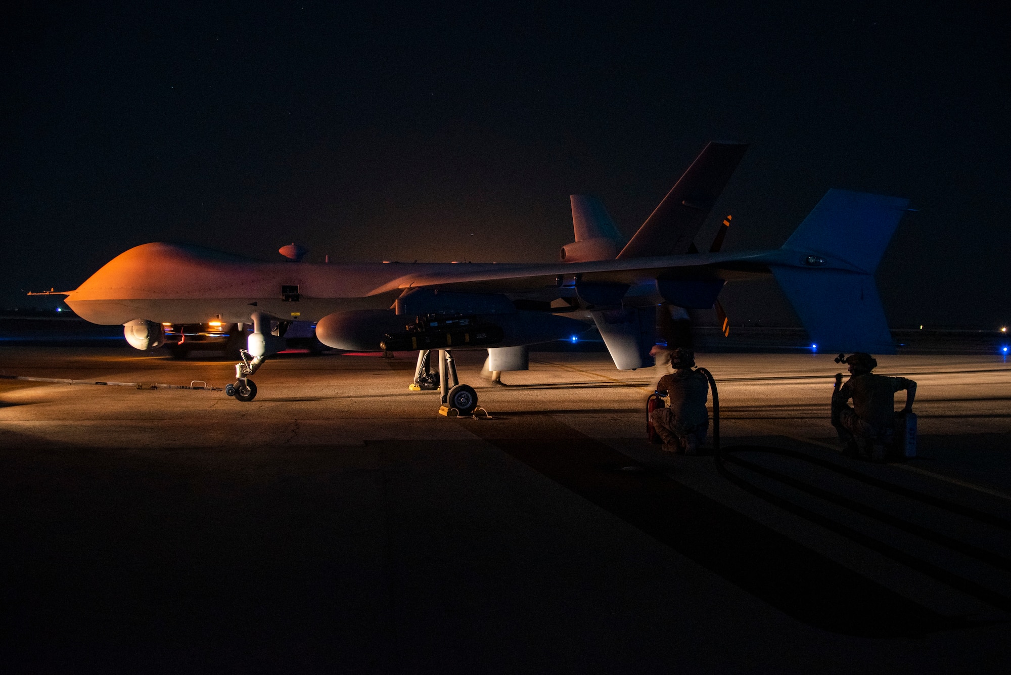 26th Expeditionary Rescue Squadron Forward Arming and Refueling Point specialists prepare to refuel a 361st Expeditionary Attack Squadron MQ-9 Reaper on a flight line at an undisclosed location, Southwest Asia, Dec. 10, 2022.  (U.S. Air Force photo by: Tech. Sgt. Jim Bentley)