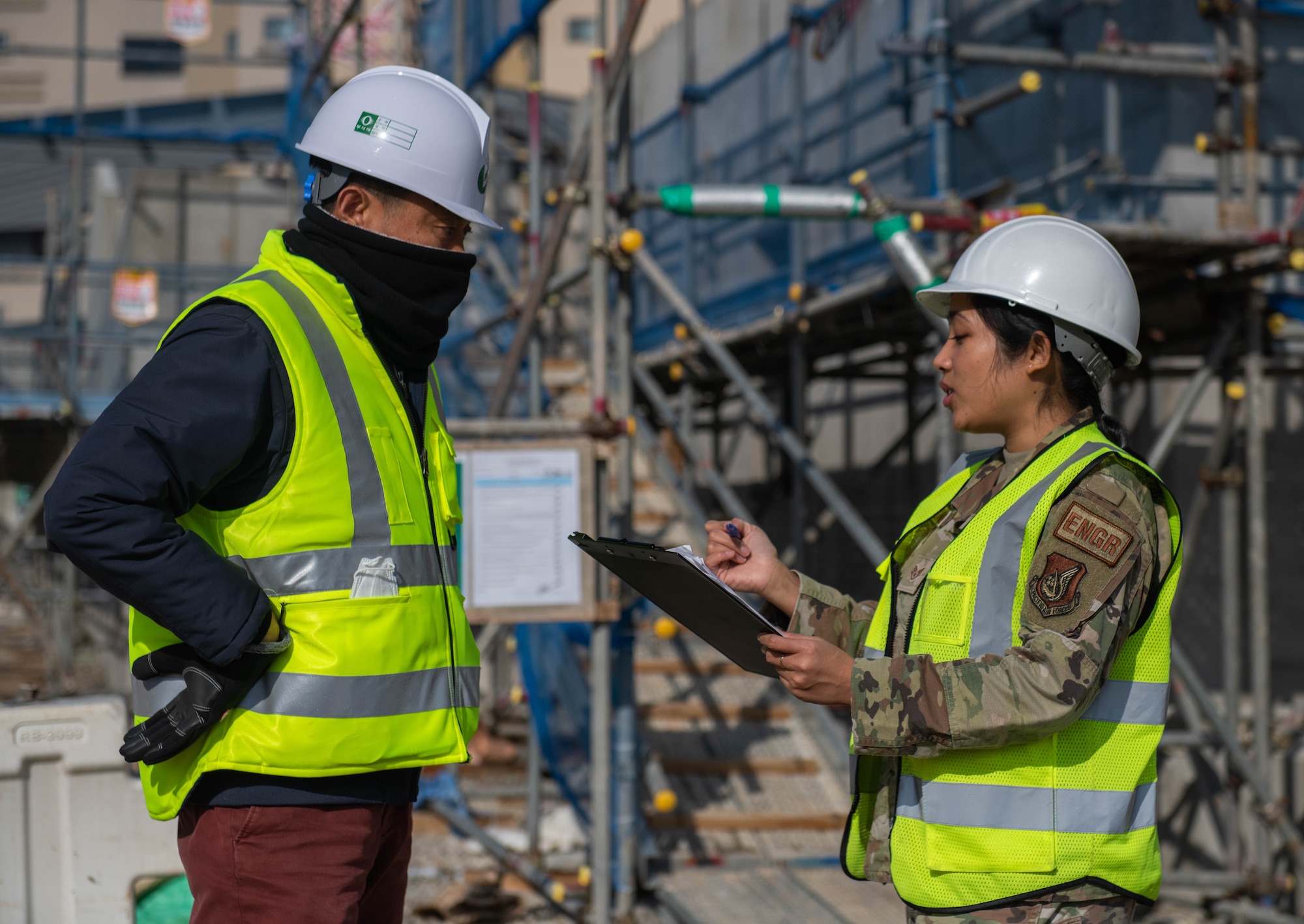 Staff Sgt. Elaine Olandez, 8th Civil Engineer Squadron construction manager, (right) consults with a construction worker on Kunsan Air Base, Republic of Korea, Dec. 15, 2022. 
Olandez also manages the wing’s Construction Escort Program where she coordinates the rotating schedule of Airmen who support the $300 million construction portfolio. (U.S. Air Force photo by 1st Lt. Cameron Silver)