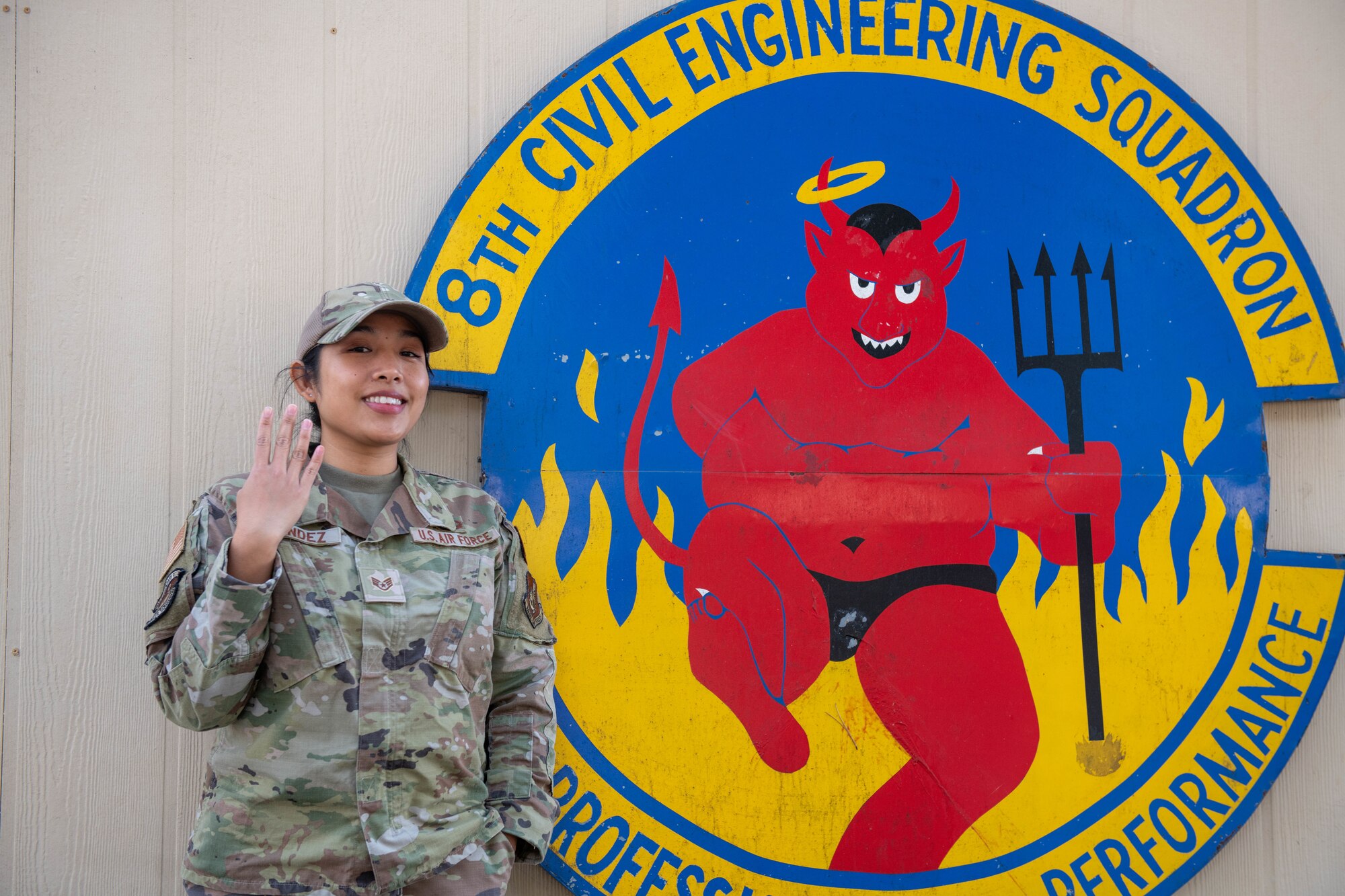 Staff Sgt. Elaine Olandez, 8th Civil Engineer Squadron construction manager, poses for a photo in front of a mural of her squadron logo on Kunsan Air Base, Republic of Korea, Dec. 15, 2022. The 8th CES, also known as the ‘Red Devils,’ point four fingers upwards to represent the pitchfork on their squadron logo. (U.S. Air Force photo by 1st Lt. Cameron Silver)