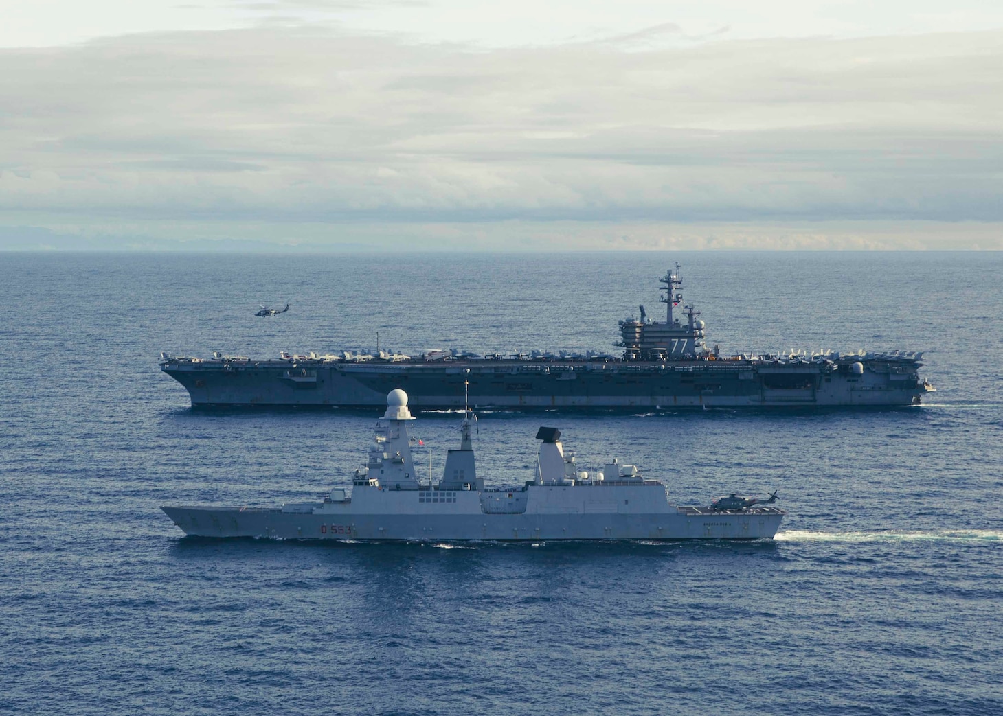 The Nimitz-class aircraft carrier USS George H.W. Bush (CVN 77) sails alongside the Italian Navy Andrea Doria-class air defense destroyer ITS Andrea Doria (D 553) while an MH-60R Knighthawk, assigned to Carrier Air Wing (CVW) 7, takes off during combined operations in the Adriatic Sea, Dec. 15, 2022.