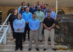 Group photo of men and women dressed in business cloths, they are standing on steps in front of the HDI Federal Center.