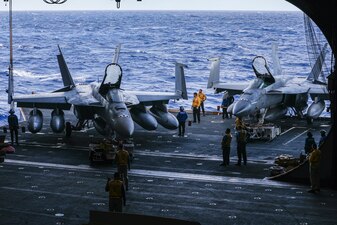 U.S. Navy Sailor guide two F/A-18E Super Hornets to the flight deck elevator aboard the aircraft carrier USS Nimitz (CVN 68).