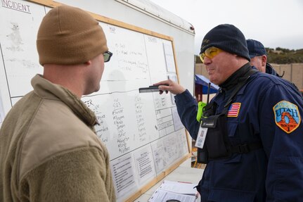 Greg Parish, a member of Utah Task Force 1, makes a plan of action with his military counterpart during a Utah National Guard FEMA Region VIII Homeland Response Force training exercise on Camp Williams, Utah, Nov. 5, 2022. The event featured multi-agency interoperability training for the Utah National Guard and civilian partner agencies to provide initial and follow-on care to stranded and injured citizens in the event of a natural or human-caused emergency.(U.S. Army National Guard photo by Sgt. Alejandro Lucero)