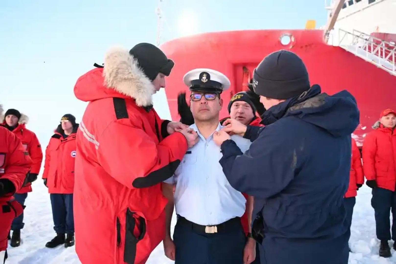 Crewmembers of the U.S. Coast Guard Cutter Healy hold an advancement ceremony for two members at the North Pole, Oct. 2, 2022. Senior Chief Petty Officer James McArdle (background) exchanges covers for Chief Petty Officer Roy Mesen Scott (center), as Chief Petty Officer Eric Heyob (left) and Petty Officer First Class Michael Underwood (right) replace his collar insignias. U.S. Coast Guard photo by Auxiliary Public Affairs Specialist 1 Deborah Heldt Cordone.