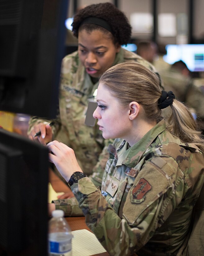 U.S. Space Force Capt. Eries Thompson, 4th Space Operations Squadron, back, works with Senior Airman Melissa Garverick, 148th Space Operations Squadron, to ensure the free flow of simulated Military Satellite Communications to United States European Command