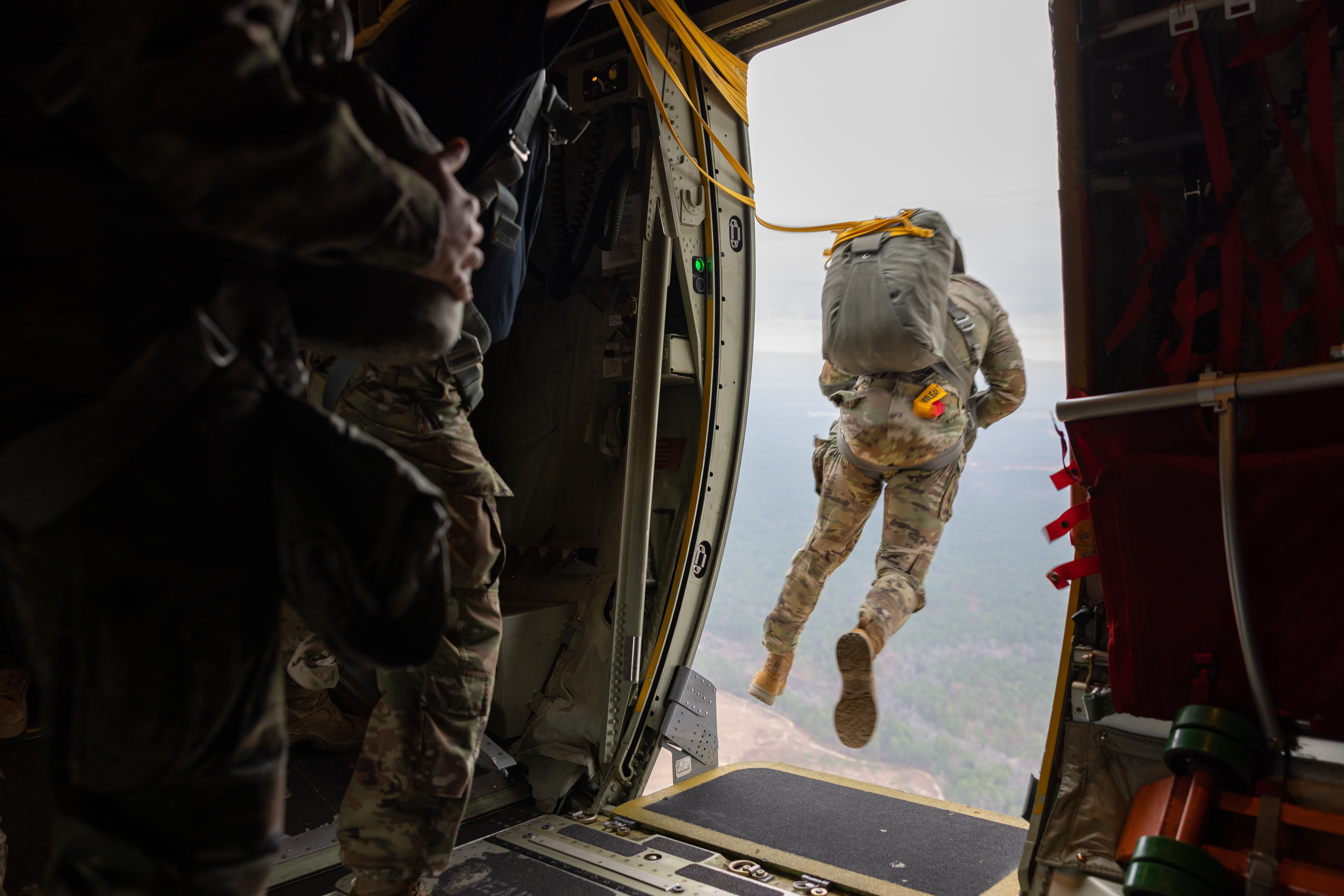 A soldier jumps out of an airborne plane.