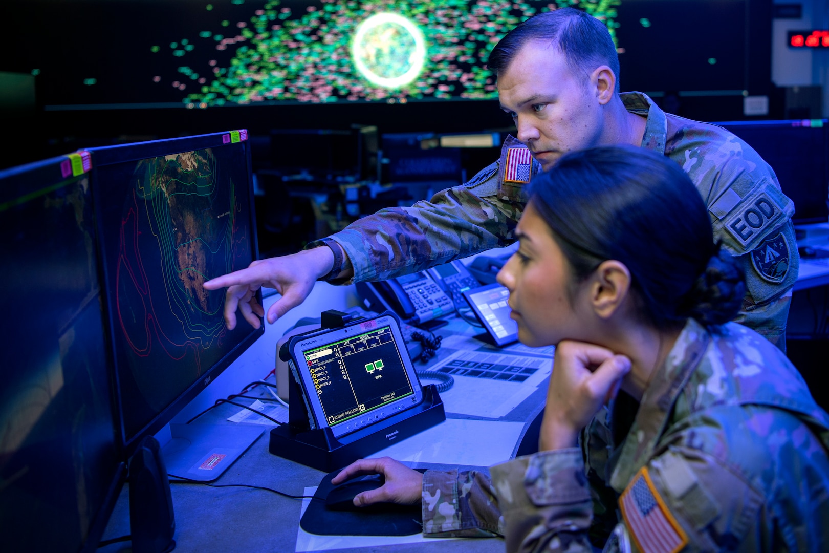 Man and woman in uniform looking at computer screen