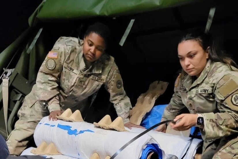 Two service members unload supplies.