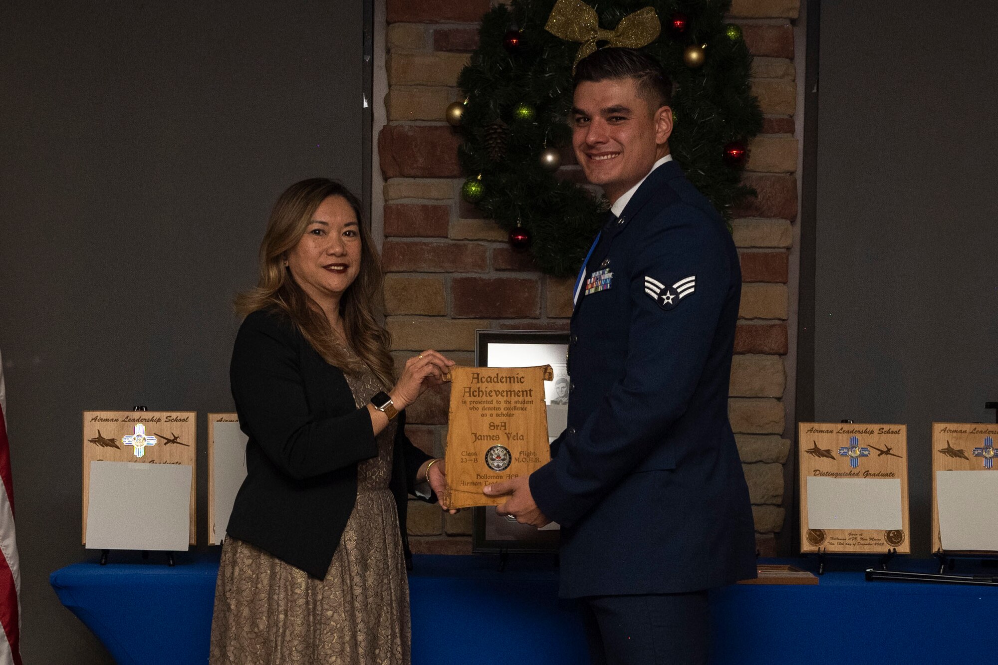 U.S. Air Force Senior Airman James Vela, right, accepts the Academic Achievement Award from Laney Cooper, Otero Federal Credit Union representative, during an Airman Leadership School graduation at Holloman Air Force Base, New Mexico, Dec. 15, 2022. The academic award is presented to the student with the highest overall average on all academic evaluations and demonstrations of leadership. (U.S. Air Force photo by Airman 1st Class Antonio Salfran)