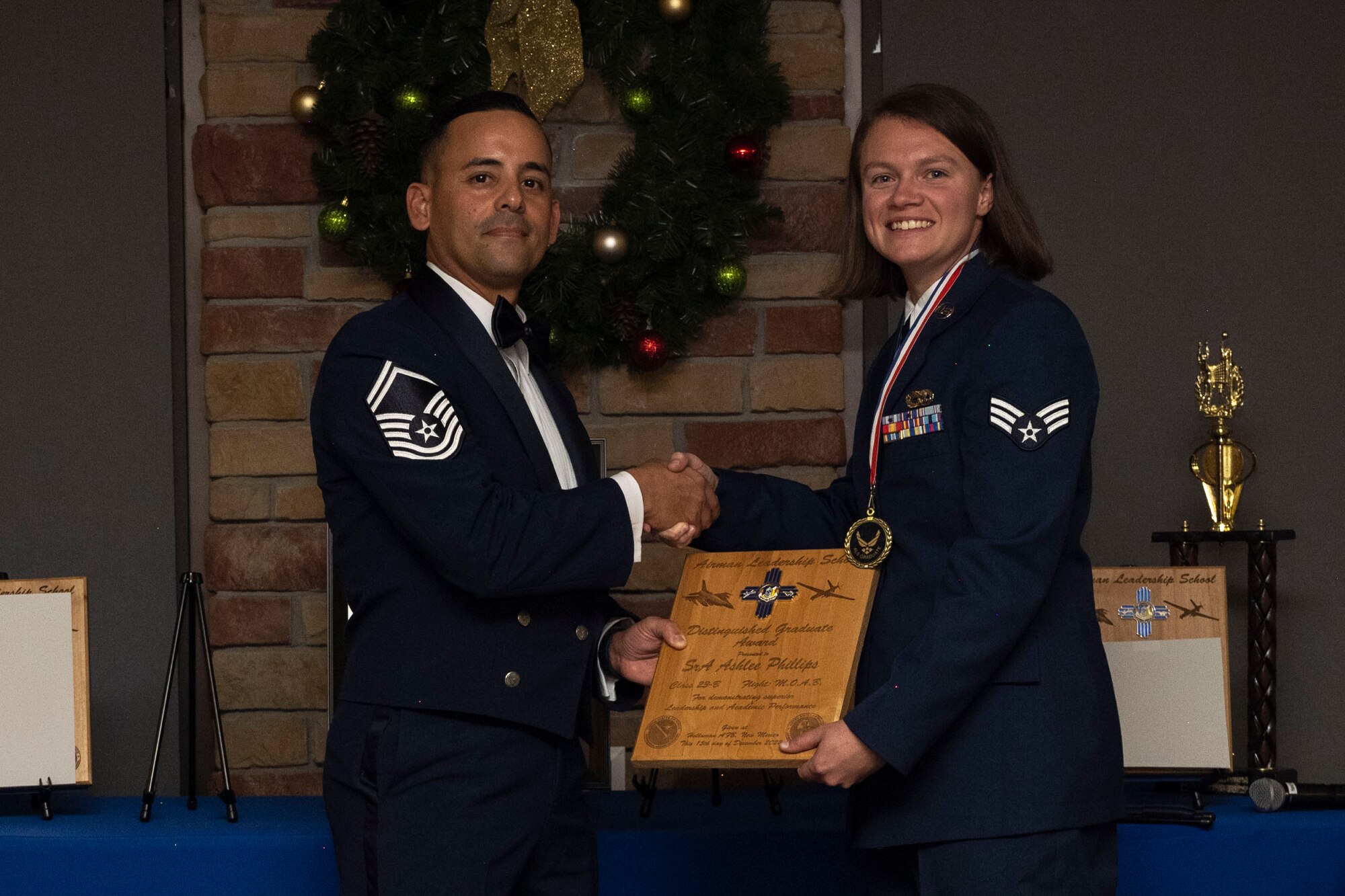 U.S. Air Force Senior Airman Ashlee Phillips, right, accepts the Distinguished Graduate Award from Holloman Top III representative Senior Master Sgt. Jaime Perez, during an Airman Leadership School graduation at Holloman Air Force Base, New Mexico, Dec. 15, 2022. The distinguished graduate award is presented to the top 10% of graduates for their performance in academic evaluations and demonstration of leadership. (U.S. Air Force photo by Airman 1st Class Antonio Salfran)