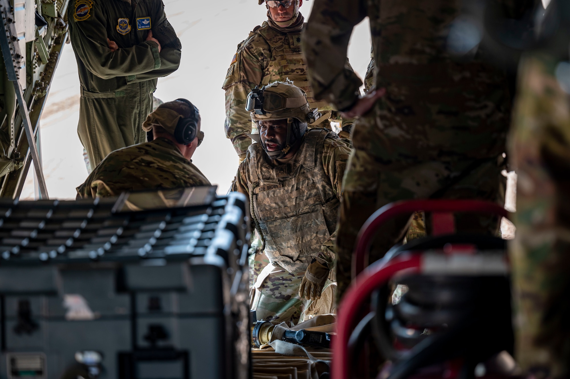 U.S. Army members assigned to the 1st Armored Division discuss preparations with 40th Airlift Squadron Airmen to refuel a M1A2 Abrams tank at Fort Bliss, Texas, Dec. 9, 2022. This exercise allowed U.S. forces to practice and showcase the interoperability and joint effectiveness for future contingency operations. (U.S. Air Force photo by Senior Airman Leon Redfern)