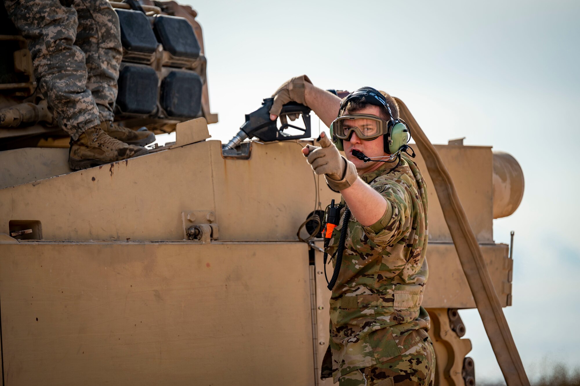 U.S. Air Force Tech. Sgt. Christopher Hofer, 40th Airlift Squadron weapons instructor, simulates refueling a M1A2 Abrams tank from a C-130J Super Hercules at Fort Bliss, Texas, Dec. 9, 2022. Dyess Air Force Base and Fort Bliss conducted a joint dry run to assess feasibility, equipment familiarization, and rehearsal of fueling operations. (U.S. Air Force photo by Senior Airman Leon Redfern)