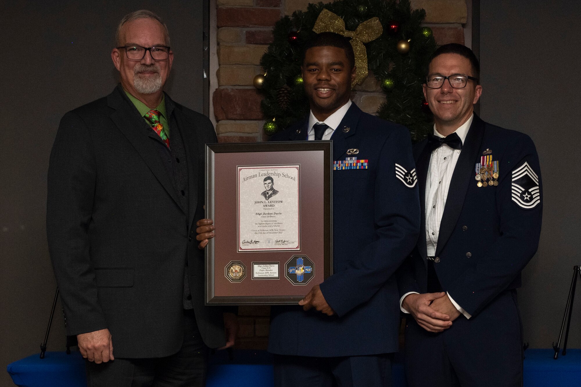 U.S. Air Force Staff Sgt. Jordan Davis, center, accepts the John L. Levitow Award from retired U.S. Chief Master Sgt. Darron Williams, left, and U.S. Air Force Chief Master Sgt. Keith Farmer during an Airman Leadership School graduation at Holloman Air Force Base, New Mexico, Dec. 15, 2022. The Levitow award is presented to the student demonstrating the highest level of leadership and scholastic performance. (U.S. Air Force photo by Airman 1st Class Antonio Salfran)