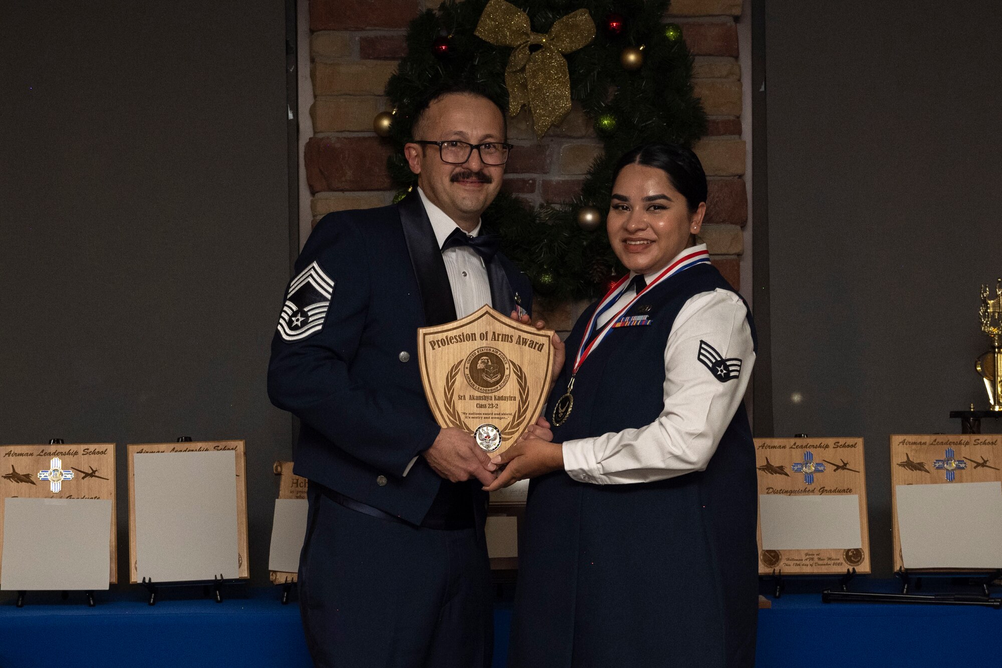 U.S. Air Force Senior Airman Akanshya Kadayira, right, accepts the Profession of Arms Award from Chief Master Sgt. Justin Romo, Airman Leadership School senior class advisor, during an Airman Leadership School graduation at Holloman Air Force Base, New Mexico, Dec. 15, 2022. The profession of arms award recognizes the student who most embodies the profession of arms, which is demonstrated with a comprehensive understanding of the warrior ethos, oath of enlistment, and the airman’s creed. (U.S. Air Force photo by Airman 1st Class Antonio Salfran)