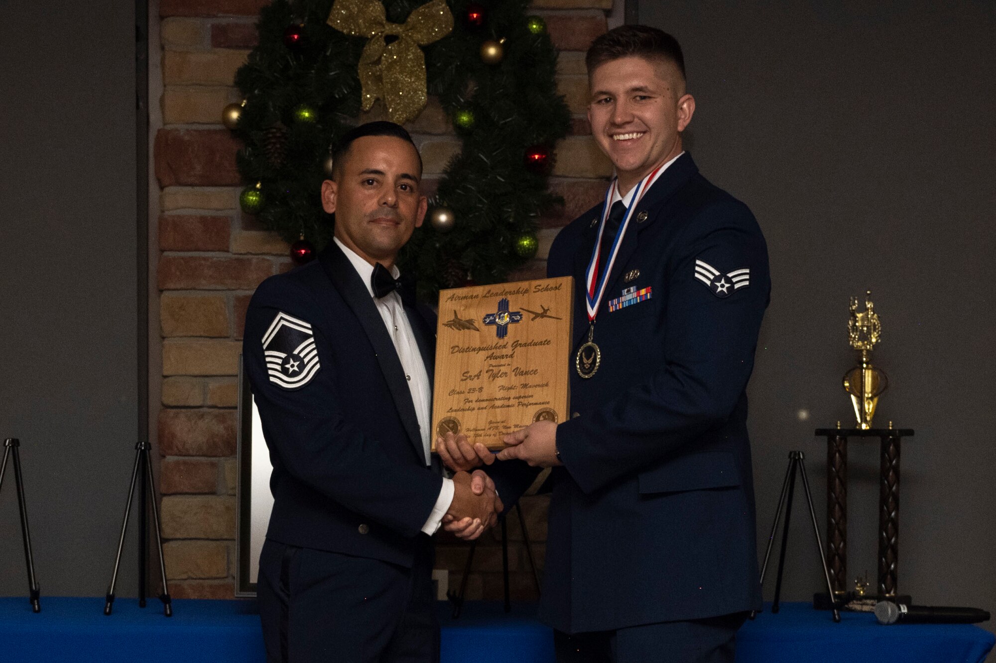 U.S. Air Force Senior Airman Tyler Vance, right, accepts the Distinguished Graduate Award from Holloman Top III representative Senior Master Sgt. Jaime Perez, during an Airman Leadership School graduation at Holloman Air Force Base, New Mexico, Dec. 15, 2022. The distinguished graduate award is presented to the top 10% of graduates for their performance in academic evaluations and demonstration of leadership. (U.S. Air Force photo by Airman 1st Class Antonio Salfran)
