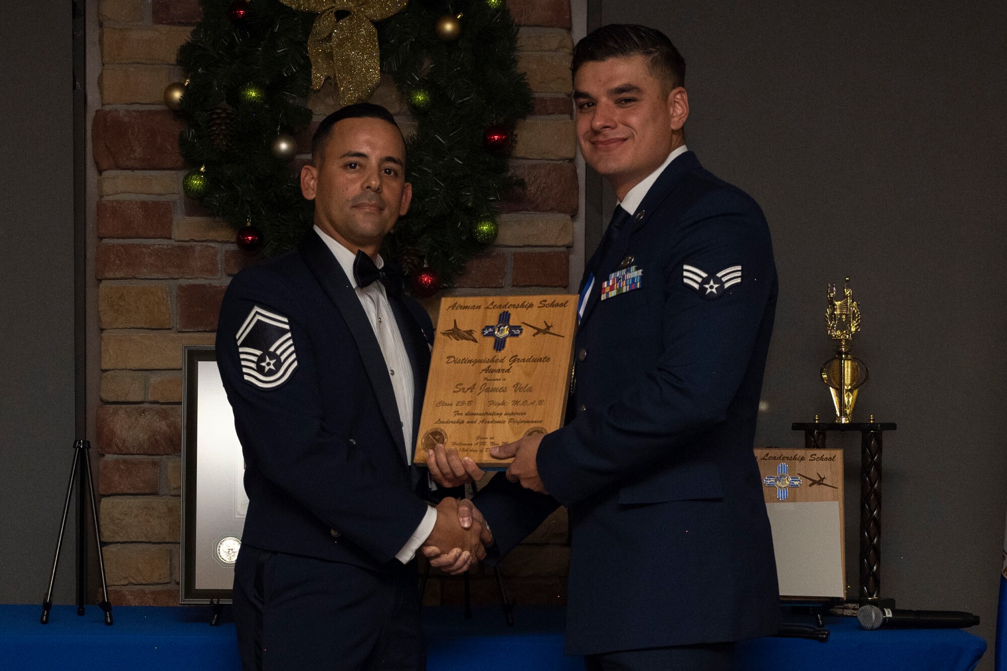 U.S. Air Force Senior Airman James Vela, right, accepts the Distinguished Graduate Award from Holloman Top III representative Senior Master Sgt. Jaime Perez, during an Airman Leadership School graduation at Holloman Air Force Base, New Mexico, Dec. 15, 2022. The distinguished graduate award is presented to the top 10% of graduates for their performance in academic evaluations and demonstration of leadership. (U.S. Air Force photo by Airman 1st Class Antonio Salfran)