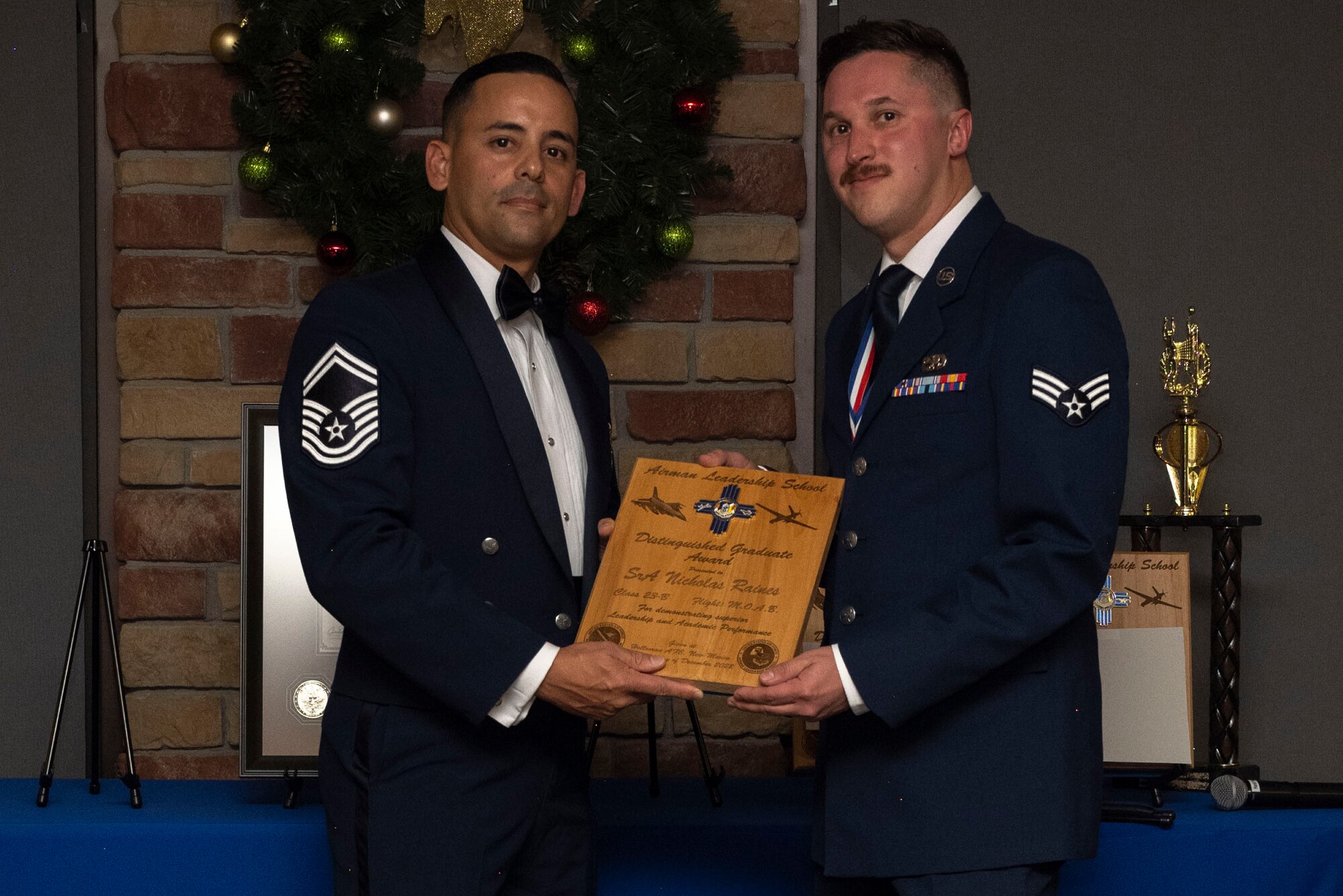 U.S. Air Force Senior Airman Nicholas Raines, right, accepts the Distinguished Graduate Award from Holloman Top III representative Senior Master Sgt. Jaime Perez, during an Airman Leadership School graduation at Holloman Air Force Base, New Mexico, Dec. 15, 2022. The distinguished graduate award is presented to the top 10% of graduates for their performance in academic evaluations and demonstration of leadership. (U.S. Air Force photo by Airman 1st Class Antonio Salfran)
