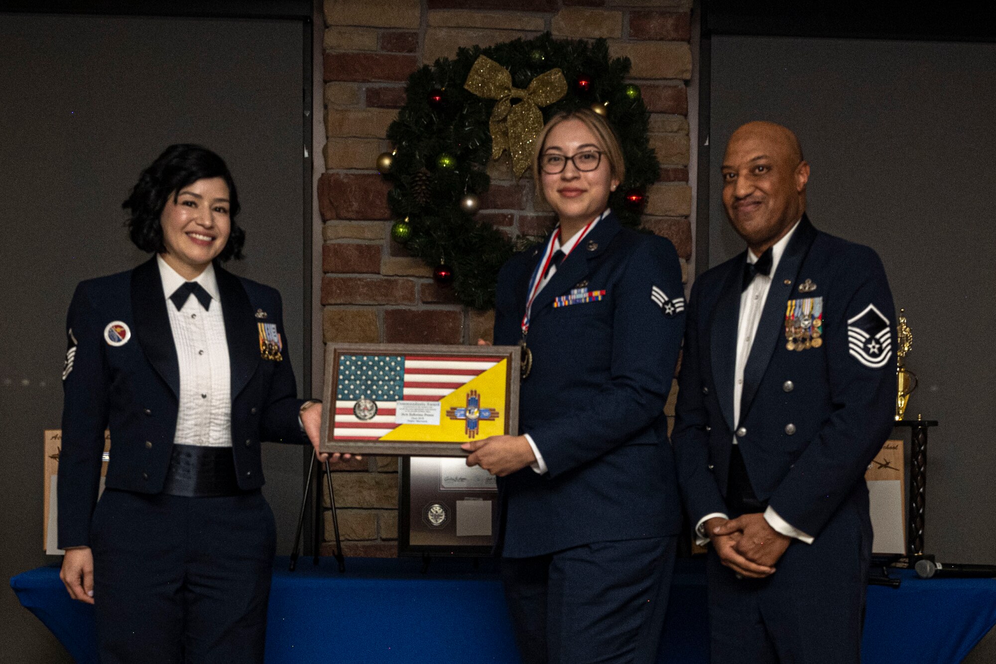 U.S. Air Force Senior Airman Zeferine Perez, Middle, accepts the Commandant's Award from U.S. Air Force Master Sgt. Cecilia Ayon, Airman Leadership School commandant, left, and retired Master Sgt. Roland Cooper, Air force Sergeants Association chapter 157 president, right, during an Airman Leadership School graduation at Holloman Air Force Base, New Mexico, Dec. 15, 2022. The Commandant’s award is selected by the ALS commandant and is presented to the student who best demonstrates the characteristics of an effective leader. (U.S. Air Force photo by Airman 1st Class Antonio Salfran)