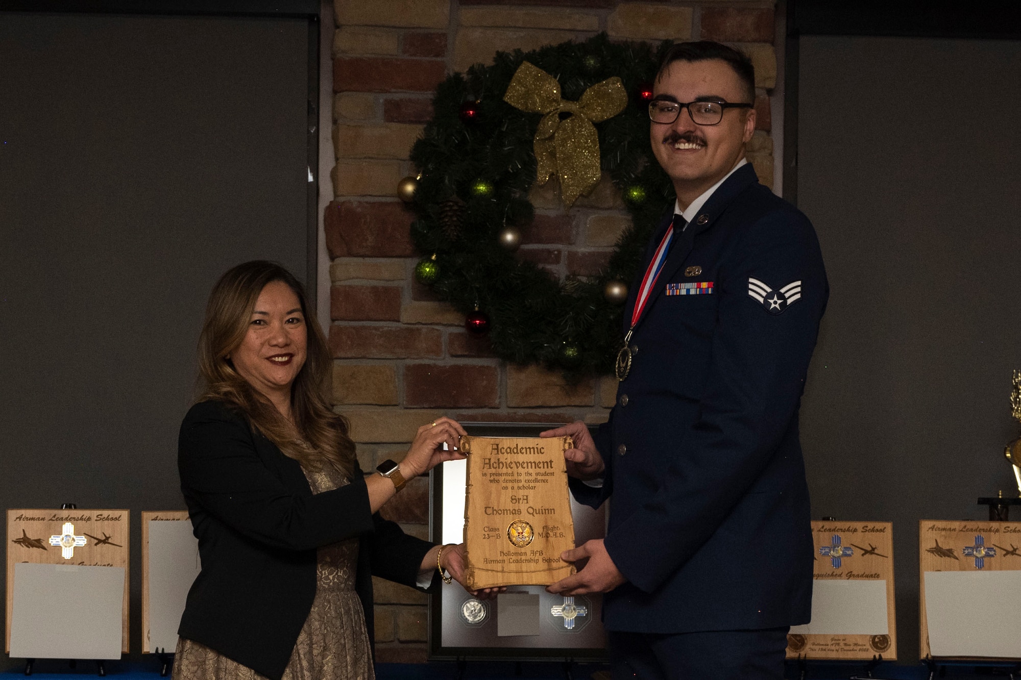U.S. Air Force Senior Airman Thomas Quinn, right, accepts the Academic Achievement Award from Laney Cooper, Otero Federal Credit Union representative, during an Airman Leadership School graduation at Holloman Air Force Base, New Mexico, Dec. 15, 2022. The academic award is presented to the student with the highest overall average on all academic evaluations and demonstrations of leadership. (U.S. Air Force photo by Airman 1st Class Antonio Salfran)