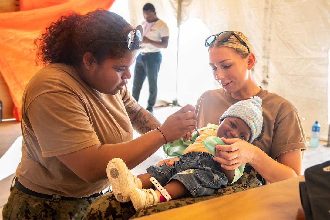 221216-N-LP924-1115 JEREMIE, Haiti (Dec. 16, 2022) Hospitalman Lauren Denise Taylor, from Houston, Texas, and Hospitalman Kristen Perry, from Los Angeles, California, assigned to the hospital ship USNS Comfort (T-AH20), take a baby’s temperature during Continuing Promise 2022 at a medical site in Jeremie, Haiti, Dec. 16, 2022. Comfort is deployed to U.S. 4th Fleet in support of Continuing Promise 2022, a humanitarian assistance and goodwill mission conducting direct medical care, expeditionary veterinary care, and subject matter expert exchanges with five partner nations in the Caribbean, Central and South America. (U.S. Navy photo by Mass Communication Specialist 3rd Class Sophia Simons)