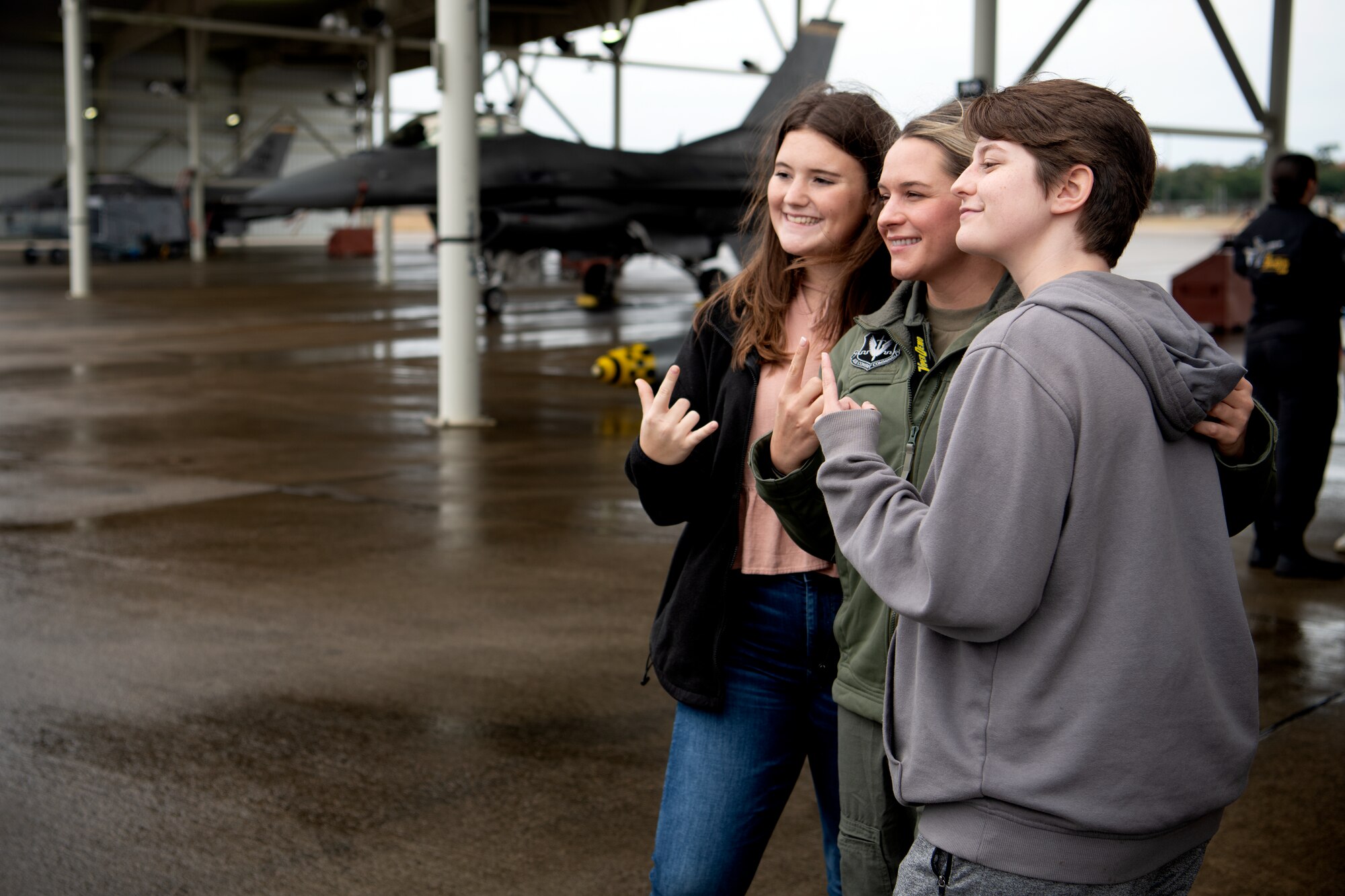 U.S. Air Force Capt. Aimee “Rebel” Fiedler, Air Combat Command F-16 Viper Demonstration Team commander, poses for a photo with two Florence 1 School District’s Advantage Academy students at Shaw Air Force Base, S.C., Nov. 30, 2022. Units from Ninth Air Force (Air Forces Central), 15th Air Force and the 20th Fighter Wing worked together to host an engagement for 35 local high school students as part of Project Quesada. The new Air Combat Command-led program is designed to attract and recruit talented students seeking careers in aviation, science, technology, engineering and math in an effort to develop future aviators and leaders. (U.S. Air Force photo by Staff Sgt. Kelsey Owen)
