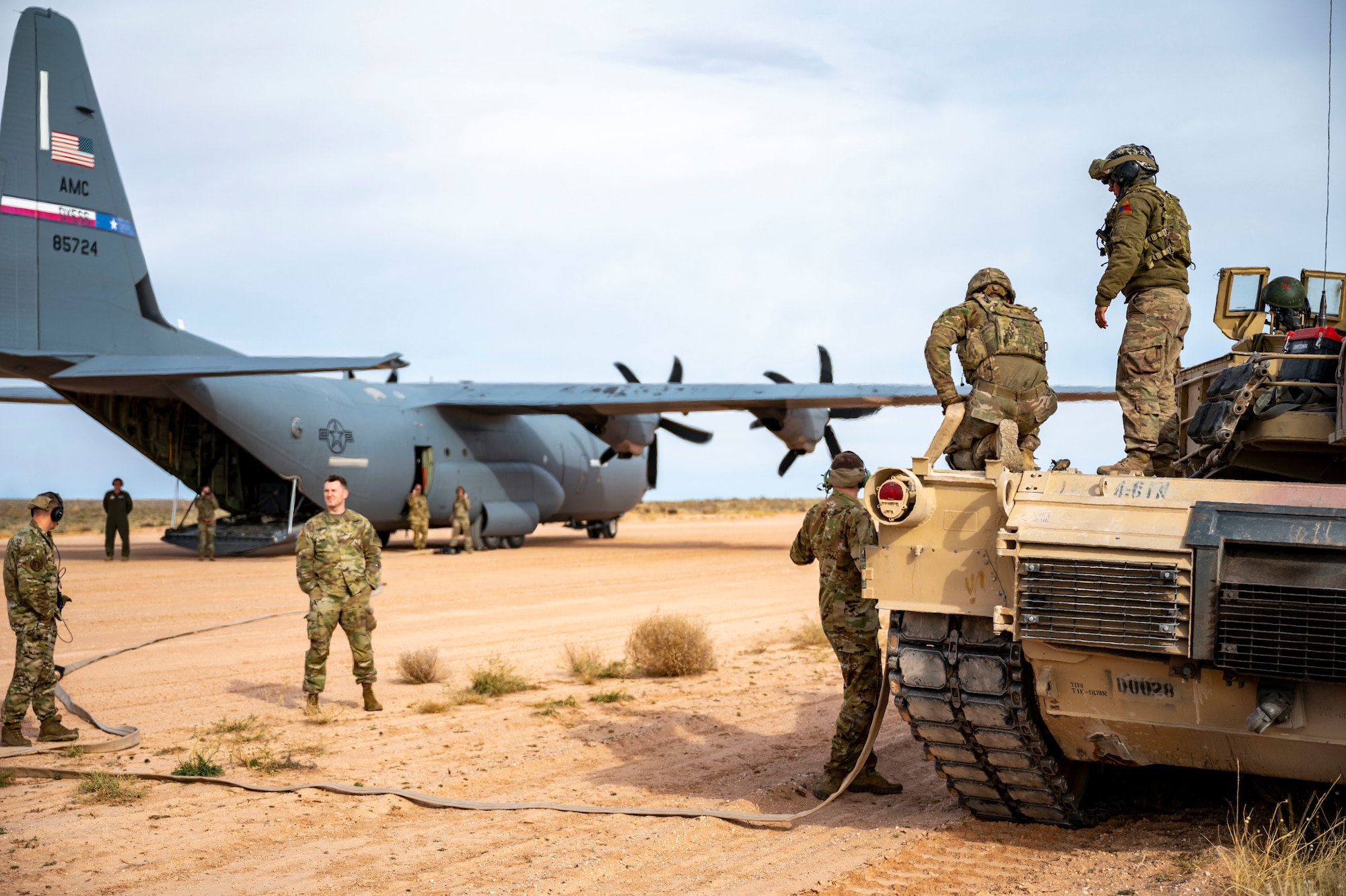 U.S. Army members assigned to the 1st Armored Division and 40th Airlift Squadron Airmen simulate refueling a M1A2 Abrams tank from a C-130J Super Hercules at Fort Bliss, Texas, Dec. 9, 2022. Hot pit refueling allows aircraft to receive or provide fuel without being shut down, implementing quicker refueling and shorter down time. (U.S. Air Force photo by Senior Airman Leon Redfern)
