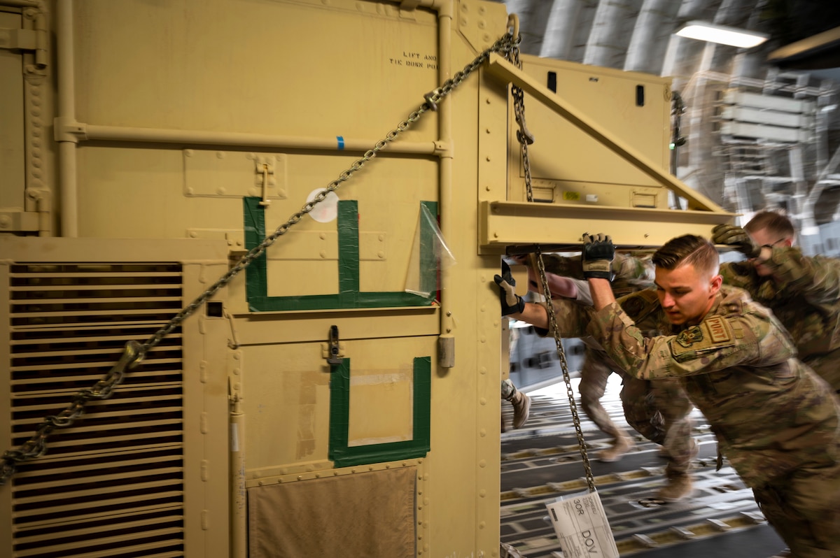 U.S. Air Force Senior Airman Norbert Kwiatkowski, 443rd Air Expeditionary Squadron Air Mobility Flight load planner, pushes a ground control station onto a C-17 Globemaster III at Al Asad Air Base, Iraq, Dec. 12, 2022. Four total ground control stations were rapidly loaded onto the aircraft. (U.S. Air Force photo by Staff Sgt. Dalton Williams)