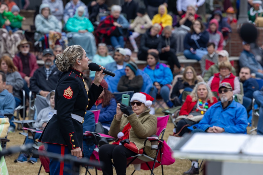 A Marine in a formal uniform sings in front of an audience.