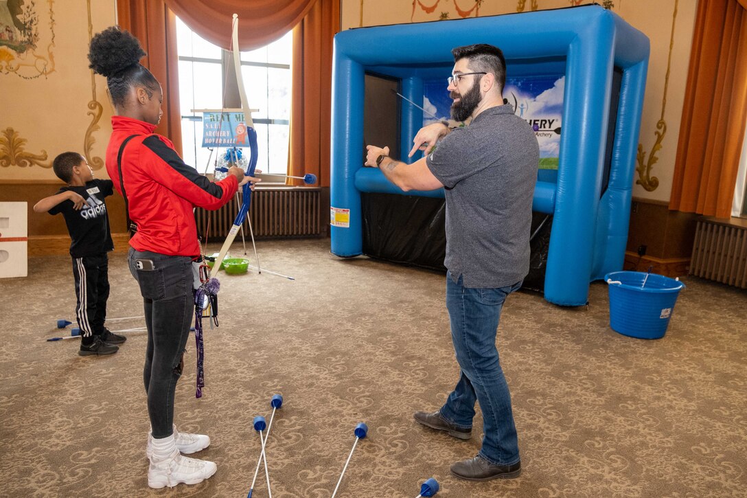 Man demonstrating archery technique to holiday party participant.