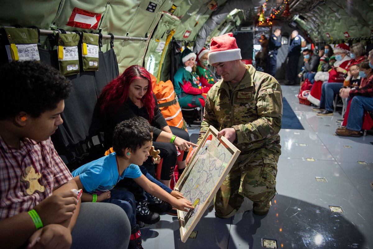 U.S. Air Force Tech. Sgt. Nick Lichtenwalner shows a map of “Route to the North Pole” to passengers, as a part of “Flight to the North Pole” event, General Mitchell International Airport, Milwaukee, Wisconsin, Dec. 10, 2022. Onboard the KC-135 jet, families and children explored the aircraft and interacted with service members. (U.S. Air National Guard photo by Staff Sgt. Josh Halverson)