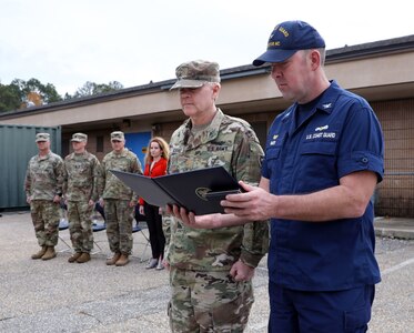 U.S. Coast Guard Capt. Matt Baer, right, sector commander of North Carolina, presents U.S. Army Maj. Kenneth Leahy, left, the North Carolina National Guard state dental officer, with the Coast Guard Commendation Medal at the NCNG Medical Readiness Detachment on Dec. 3, 2022. Leahy was recognized for his heroism in saving a distressed 10-year old child from drowning in the ocean over 200 yards from shore.