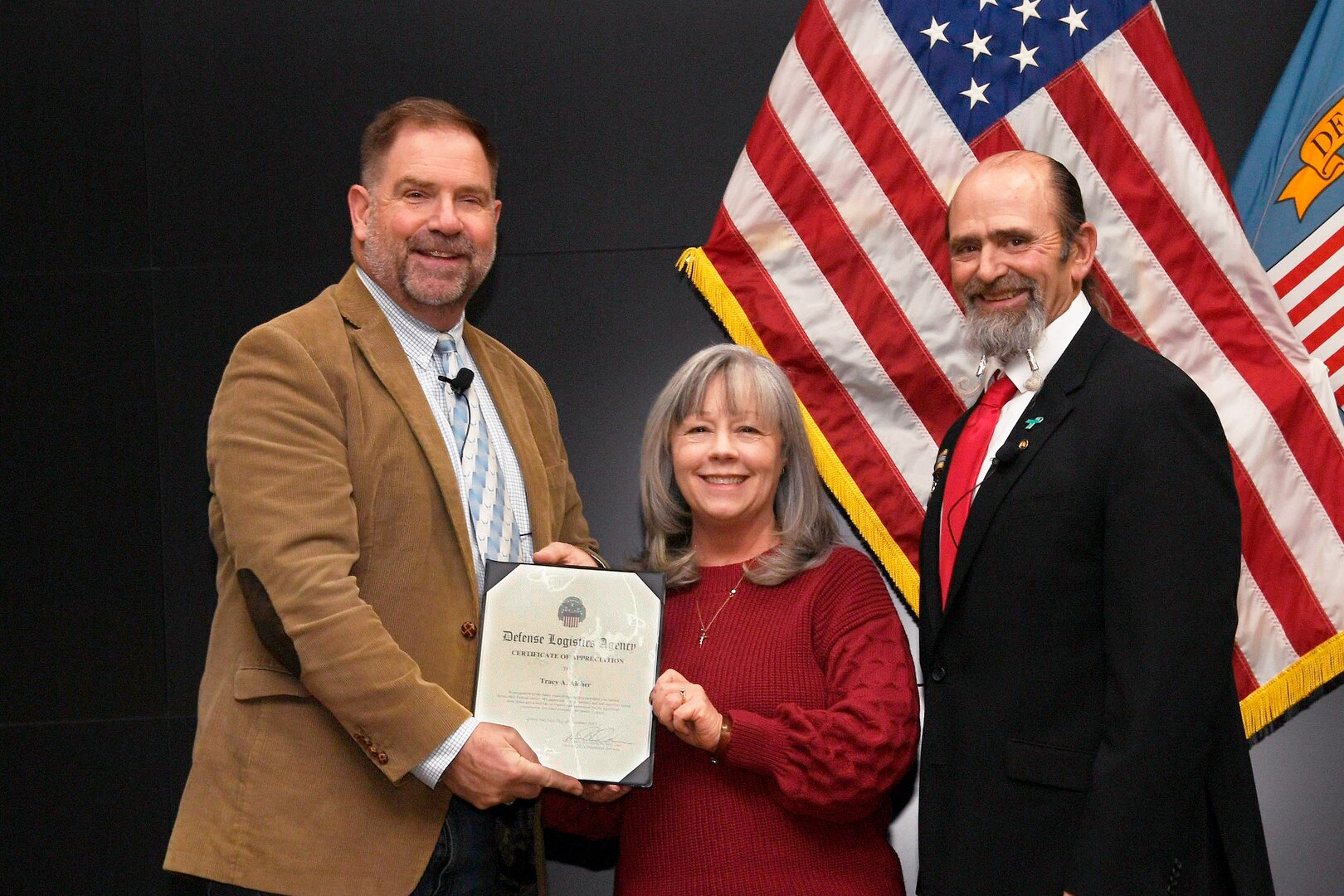 Two men and woman in a group photo holding an award.