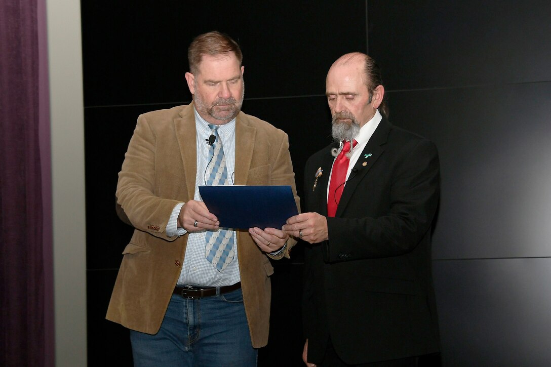 Two men reviewing award citation.