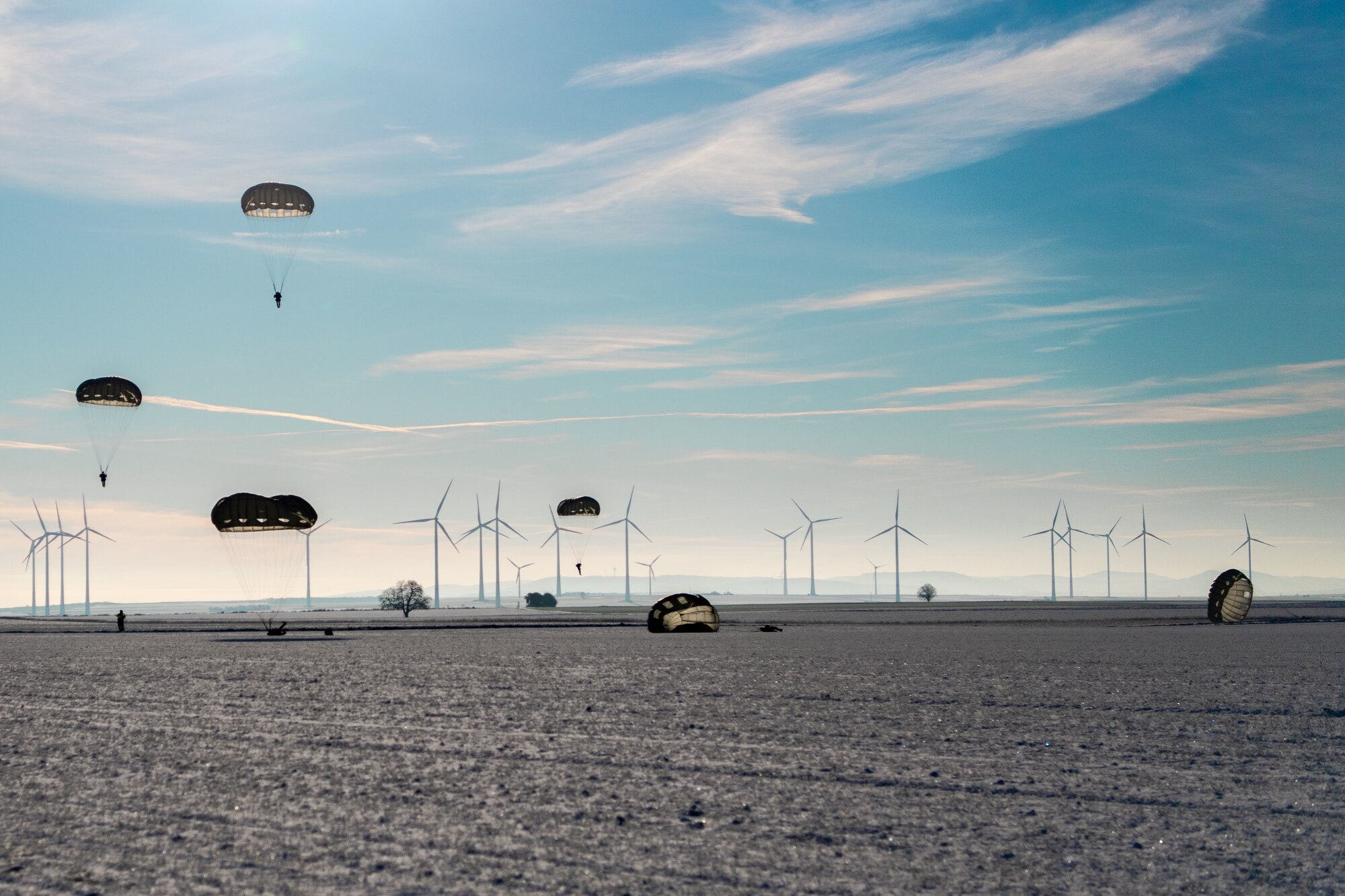 Service members from five NATO Countries land after a static line jump at Alzey Drop Zone, Ober-Flörsheim, Germany, Dec. 16, 2022