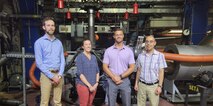 From left to right: Aidan Cowhig, Liana Sansom, Brian Noyes and Dr. Abel Vargas in front of a helicopter drive train on a test mount at Naval Air Systems Command in Patuxent River, Md., on July 15, 2022. (Photo provided by Liana Sansom)