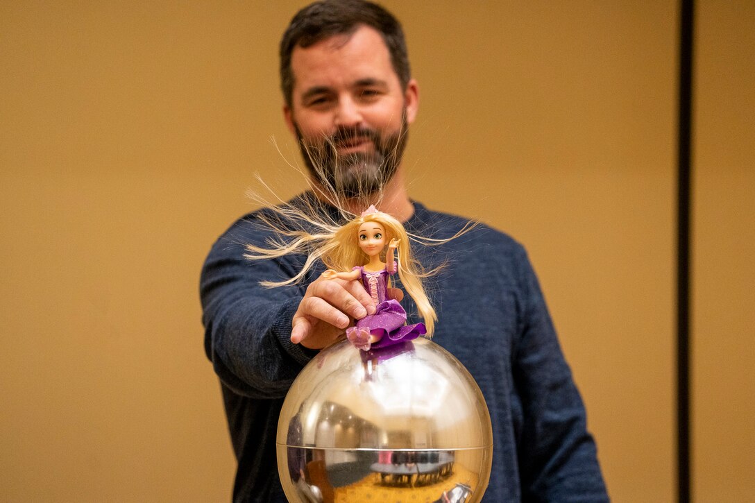 IMAGE: Naval Surface Warfare Center Dahlgren Division’s (NSWCDD) Michael Clark uses a Van De Graaff generator to demonstrate the effect of static electricity on the hair of a Rapunzel doll. Clark joined other NSWCDD personnel in providing STEM-related presentations to Harrison Road Elementary School fifth graders during their field trip to the University of Mary Washington.