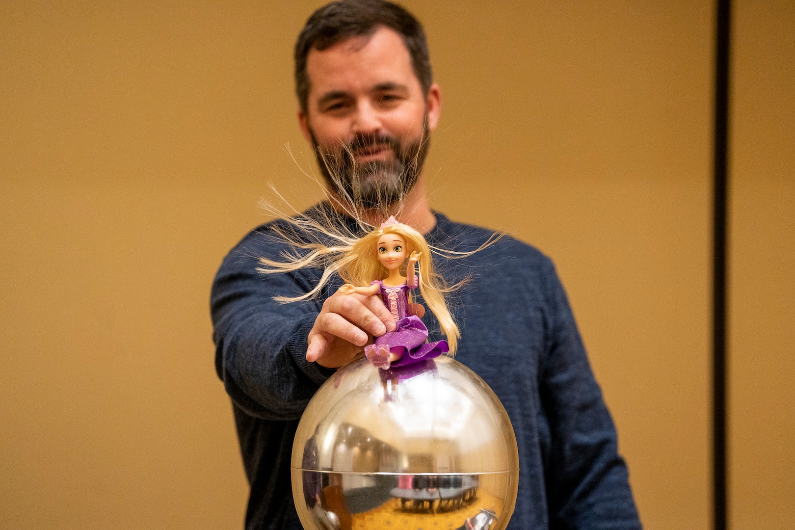IMAGE: Naval Surface Warfare Center Dahlgren Division’s (NSWCDD) Michael Clark uses a Van De Graaff generator to demonstrate the effect of static electricity on the hair of a Rapunzel doll. Clark joined other NSWCDD personnel in providing STEM-related presentations to Harrison Road Elementary School fifth graders during their field trip to the University of Mary Washington.