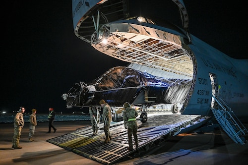 Airmen pull the fuselage of an F-22 Raptor from inside a C-5M Galaxy