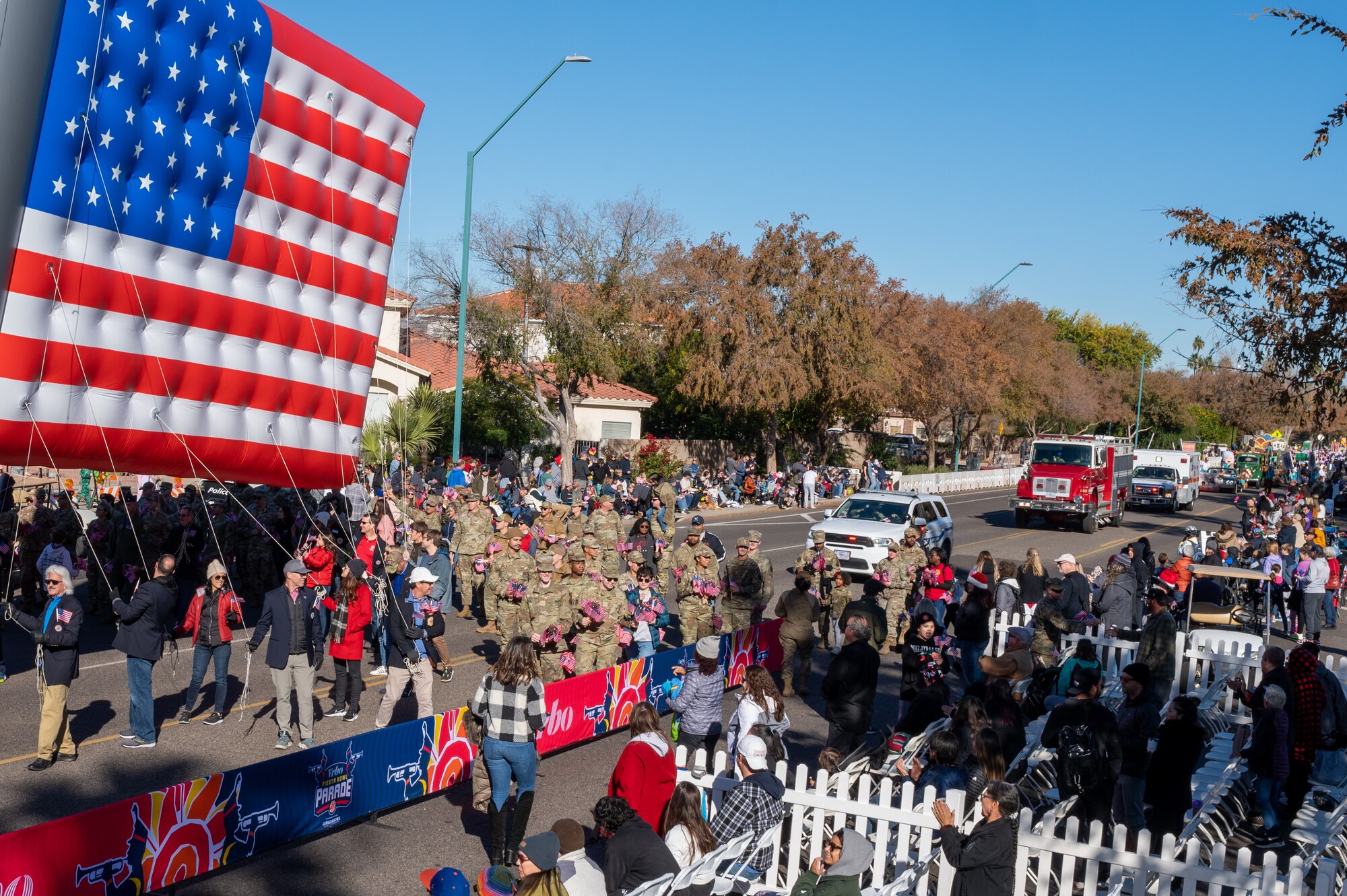 U.S. Air Force Airmen hand out American Flag souvenirs during the Fiesta Bowl Parade, Dec. 17, 2022, in Phoenix, Arizona.