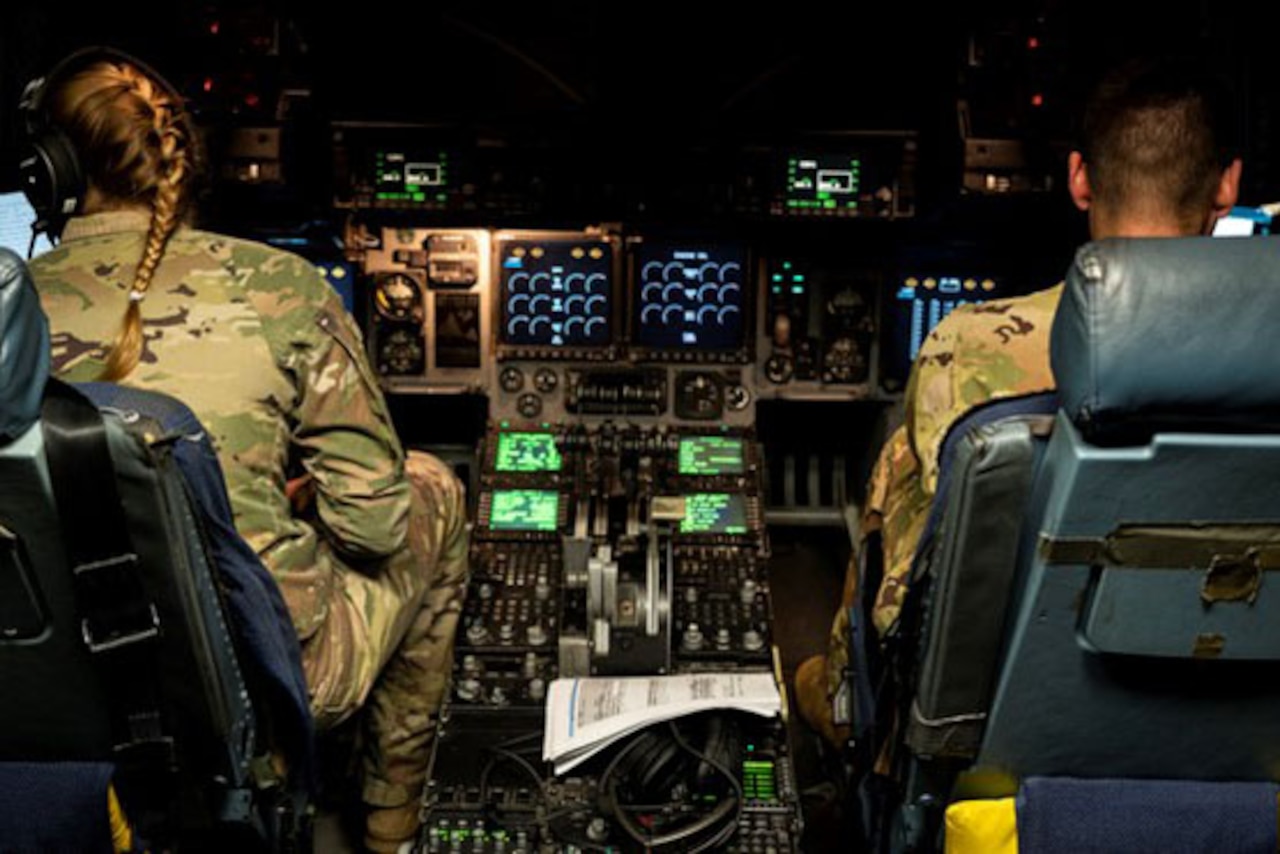 Two airmen sit in the cockpit of a plane.