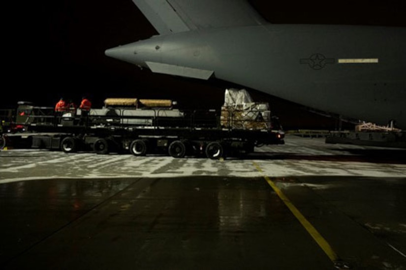 A truck filled with cargo backs up to a plane.