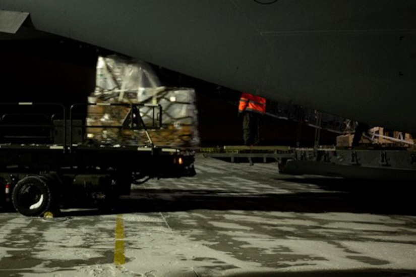 A truck laden with cargo backs up to a plane.