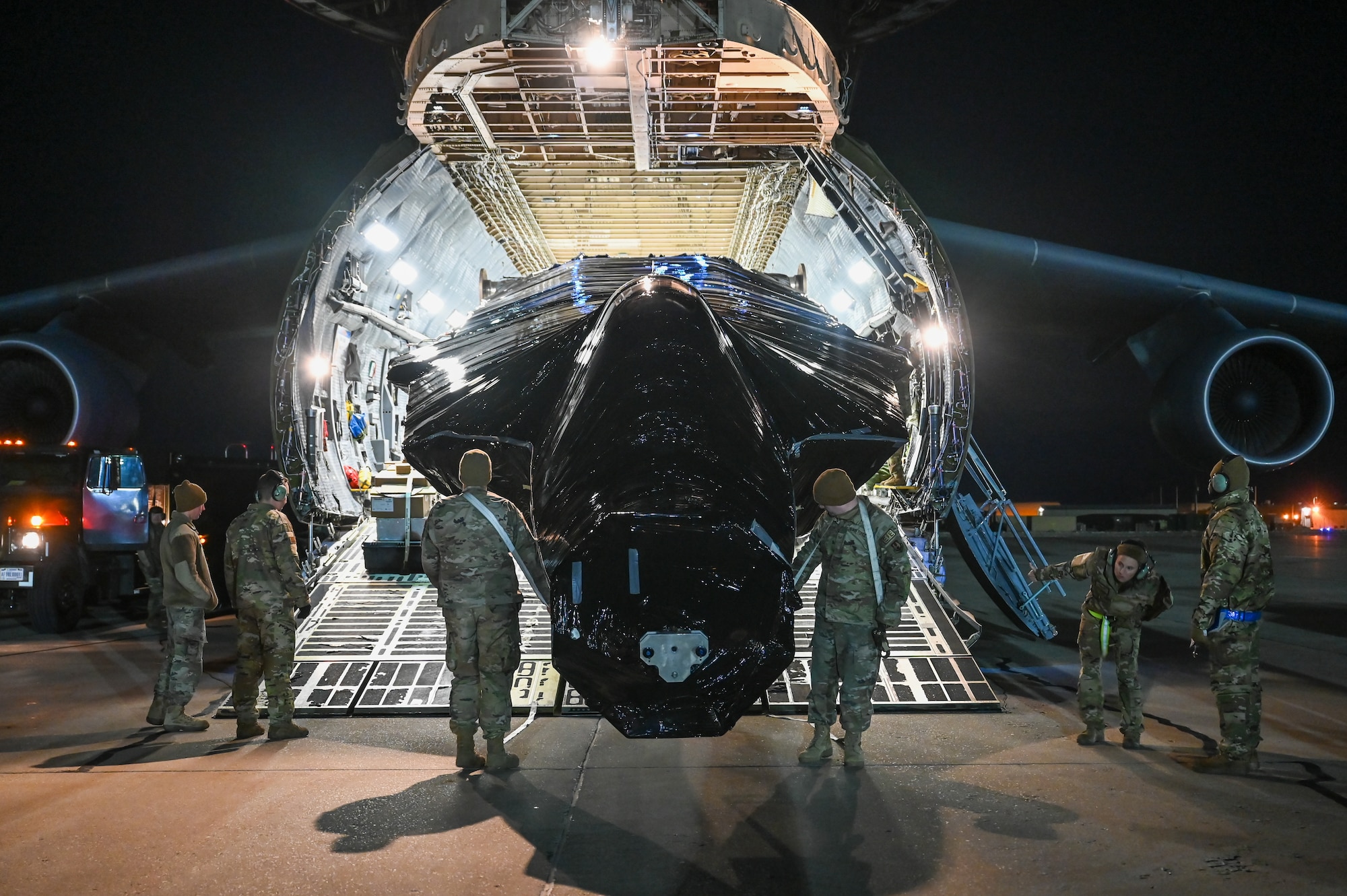 Airmen pull the fuselage of an F-22 Raptor from inside a C-5M Galaxy