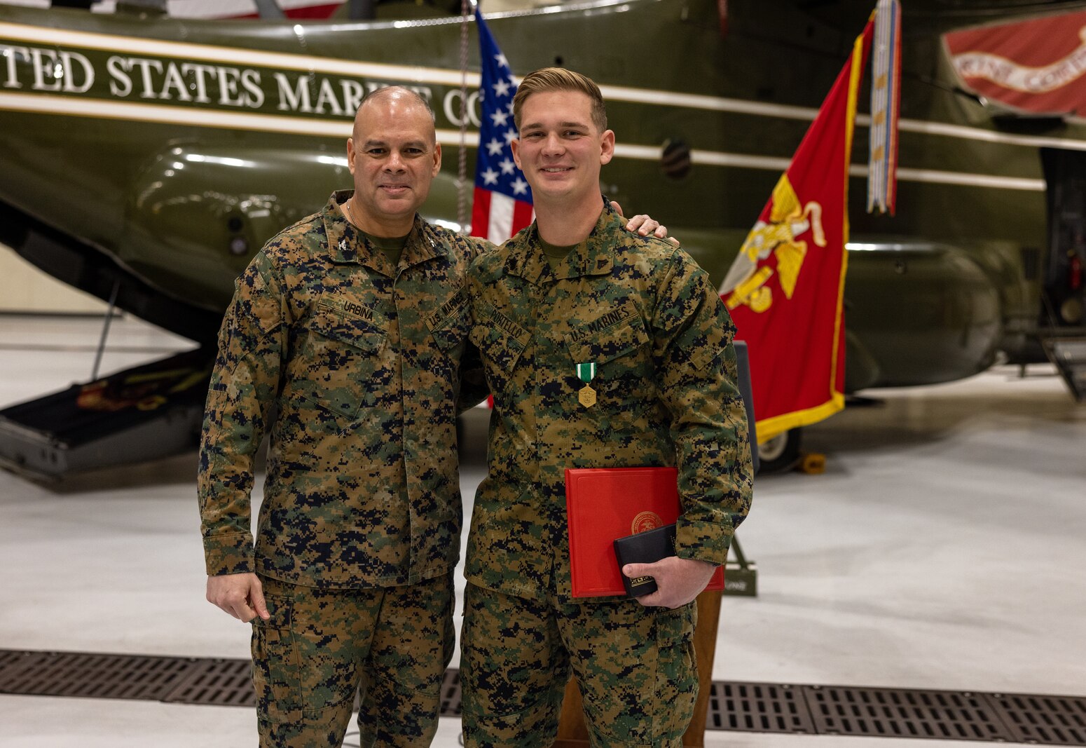 U.S. Marine Corps Cpl. Chase Portello, a noncommissioned officer with Marine Helicopter Squadron One, right, poses for a photo with U.S. Marine Corps Col. Carlos Urbina, the director of Command Element Information Division, left, after his award ceremony at Marine Corps Base Quantico, Virginia, Dec. 16, 2022. Portello received a Navy Commendation Medal for his actions on Nov. 14, 2022, saving the life of Col. Carlos Urbina. (U.S. Marine Corps photos by Lance Cpl. Joaquin Dela Torre)