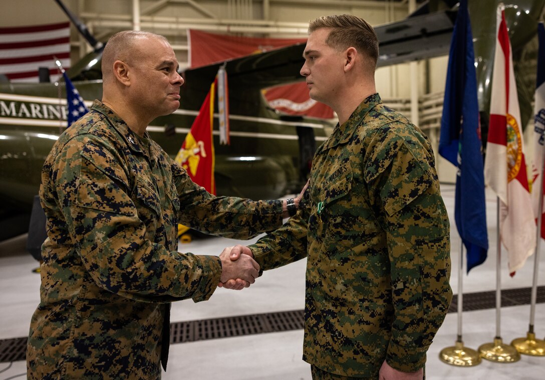 U.S. Marine Corps Cpl. Chase Portello, a noncommissioned officer with Marine Helicopter Squadron One, right, shakes hands with U.S. Marine Corps Col. Carlos Urbina, the director of Command Element Information Division, left, during his award ceremony at Marine Corps Base Quantico, Virginia, Dec. 16, 2022. Portello received a Navy Commendation Medal for his actions on Nov. 14, 2022, saving the life of Col. Carlos Urbina. (U.S. Marine Corps photos by Lance Cpl. Joaquin Dela Torre)